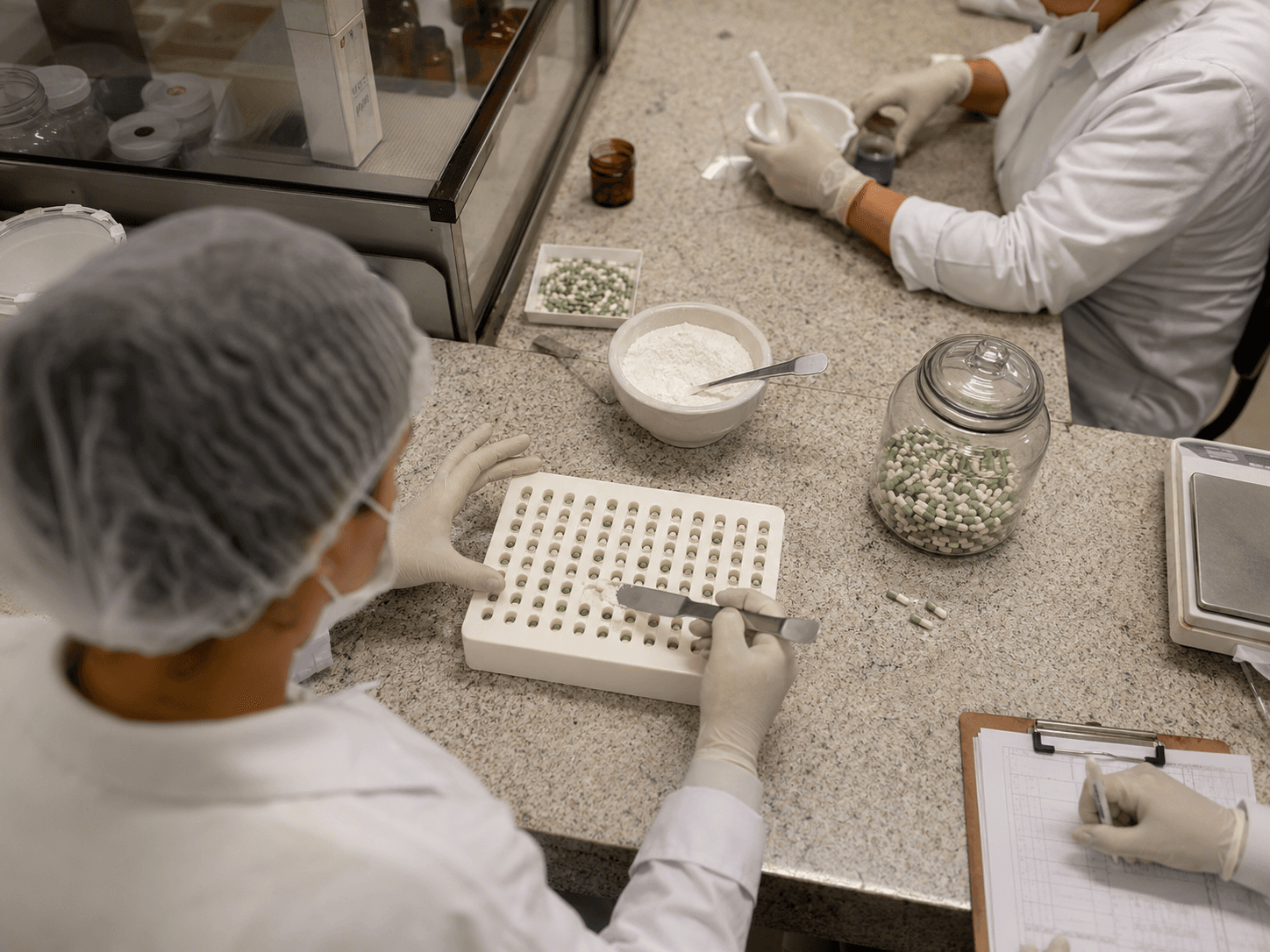 Técnicos preenchendo cápsulas no laboratório Lumia